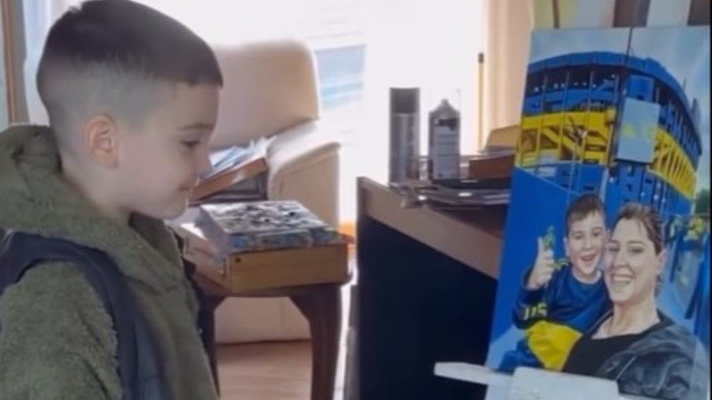 Santi mirando el cuadro de la artista Agostina Mauro, en el que lo retrató junto a su madre en la cancha de Boca.